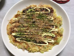 Drizzle a little okonomiyaki sauce and mayonaise on top of the okonomiyaki savory cabbage pancake. Sprinkle some katsuobushi bonito flakes and ao-nori on top and serve.