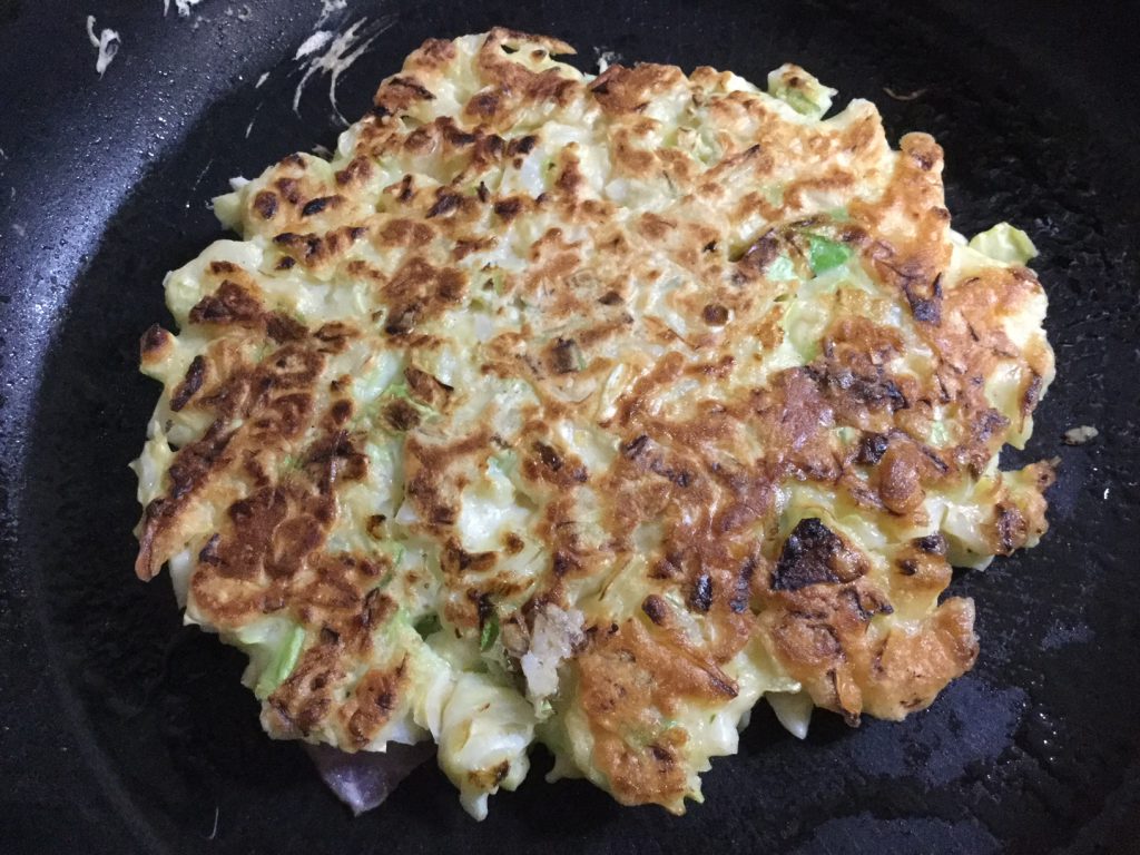 Grill the okonomiyaki savory cabbage pancake for about 4 minutes then flip it over