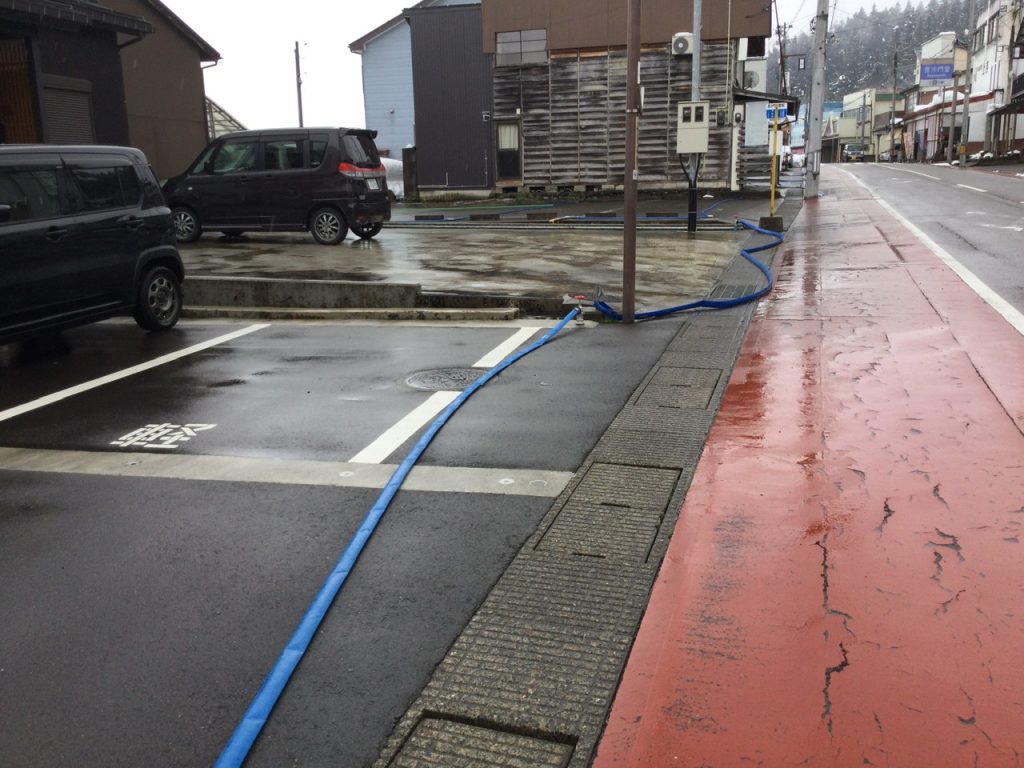 Blue snow removal hoses set up around parking lots and driveways in Minamiuonuma, Niigata, Japan